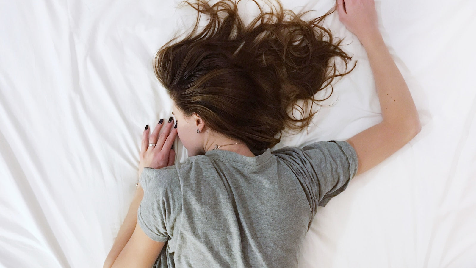 Person sleeping face down on a white bed during recovery